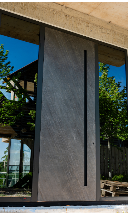 Wielkogabarytowe drzwi wejściowe z długim pionowym uchwytem i bocznymi przeszkleniami