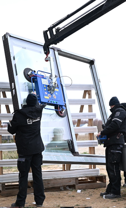 Monterzy prowadzą duże okno podnoszone dźwigiem z próżniową przyssawką