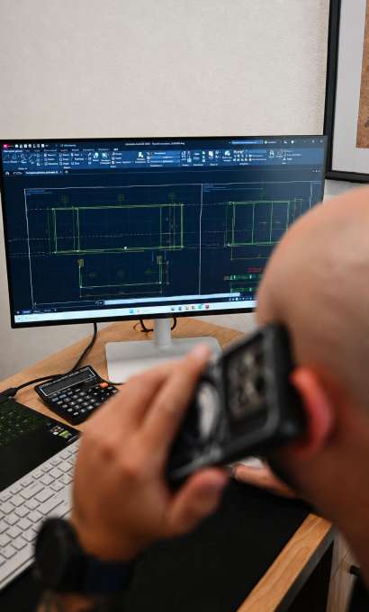 Mężczyzna rozmawia przez telefon i patrzy na rysunek techniczny na monitorze