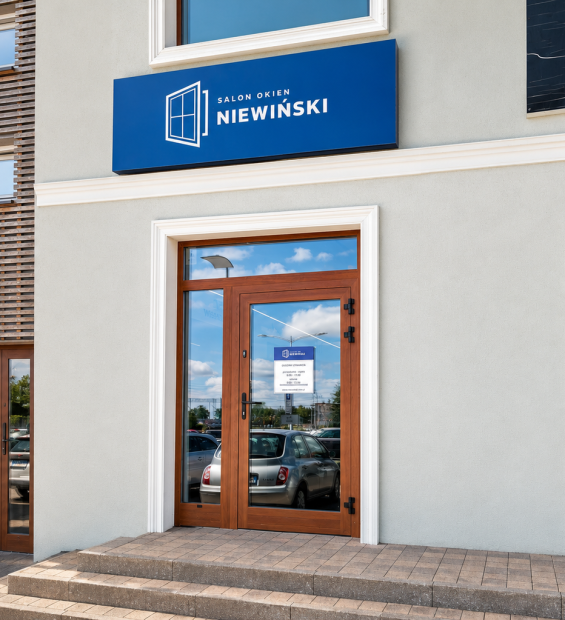 Przeszklone drzwi wejściowe Salonu Okien Niewiński ze schodami i niebieskim szyldem nad nimi